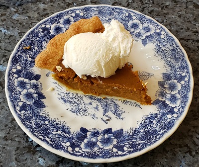 Photo of a slice of pumpkin pie and vanilla ice cream.